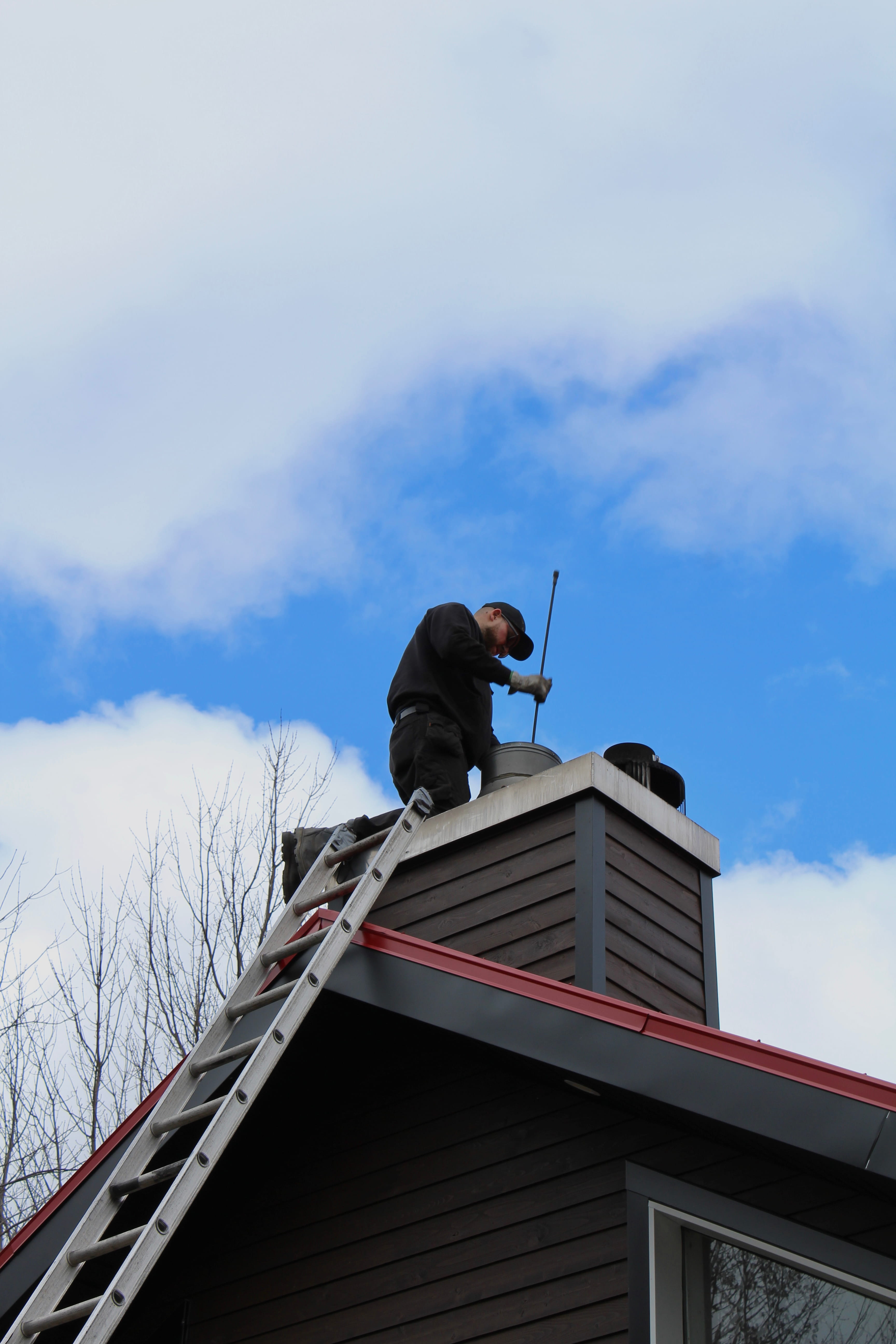 Ramonage de cheminée par un technicien RA-MO-NET sur toiture dans la grande région de Québec